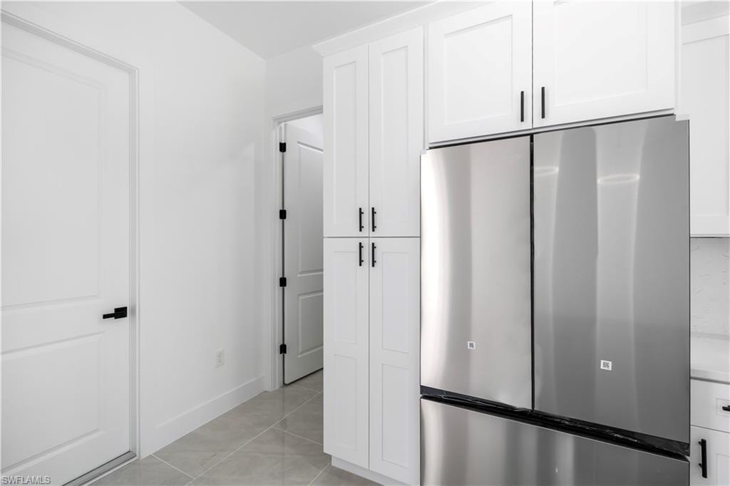 Stainless steel refrigerator and freezer unit, integrated with white shaker-style cabinetry featuring matte black hardware
