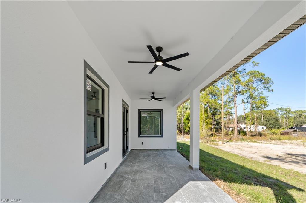 Covered patio featuring two ceiling fans, dark-framed windows, and a glass-paneled door