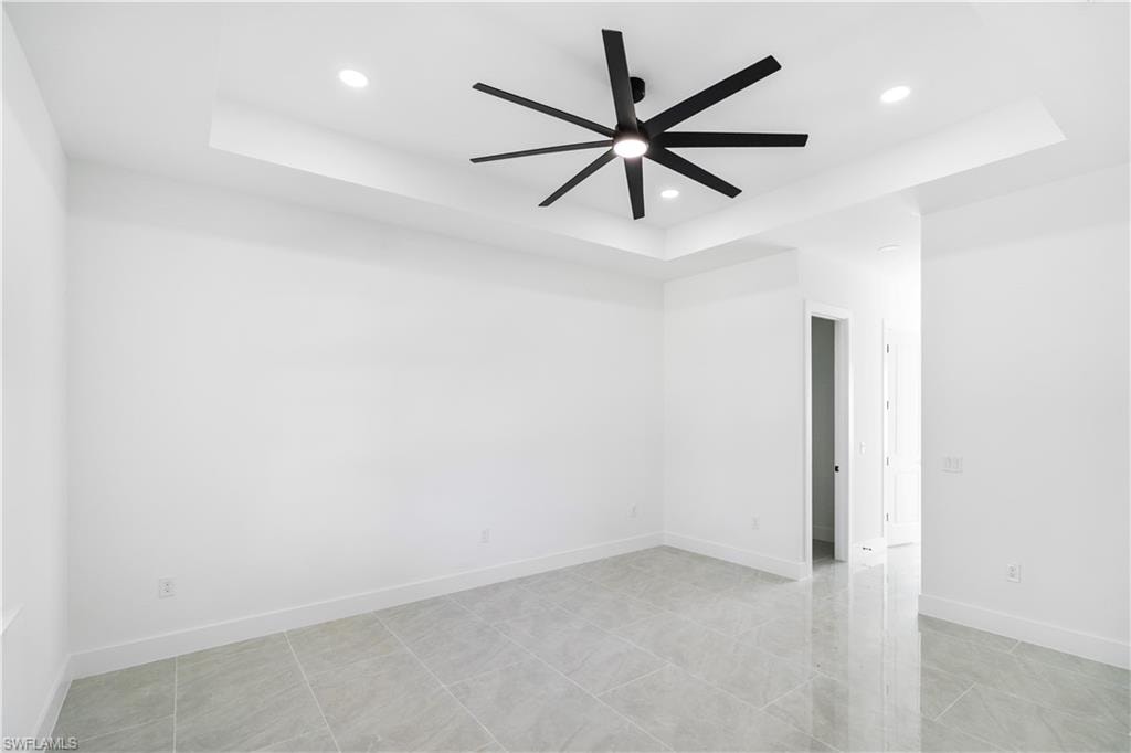 Spacious room featuring a tray ceiling with recessed lighting and a contemporary ceiling fan