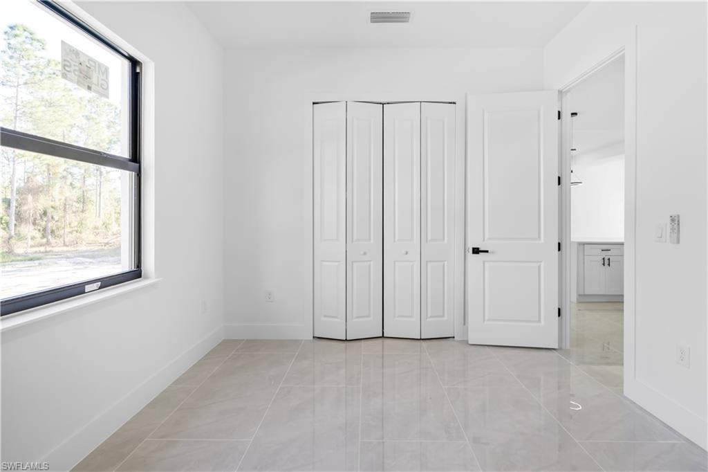 Bright room featuring large format tile flooring and a double bi-fold closet