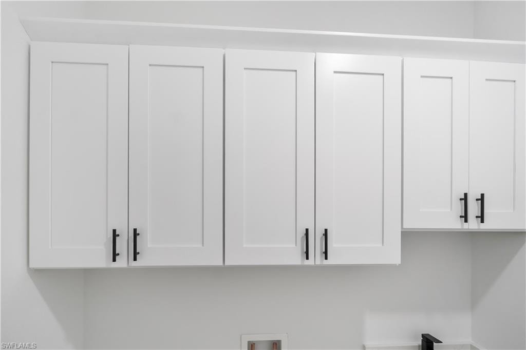 White shaker-style cabinetry with matte black hardware, featuring a crown molding detail and ample overhead storage