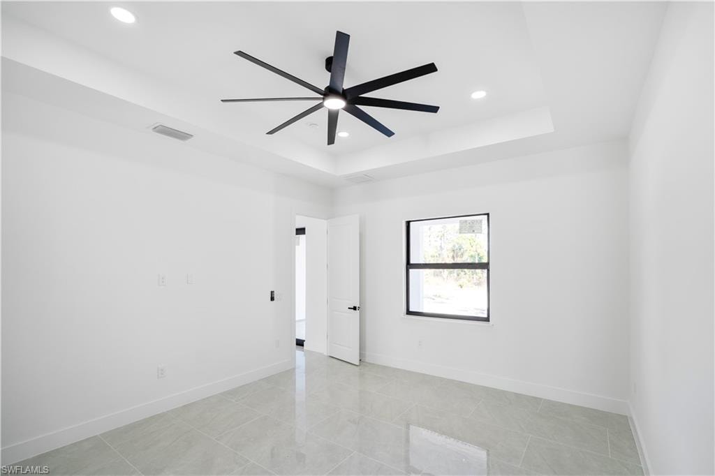 Spacious room with tray ceiling, recessed lighting, and a modern ceiling fan