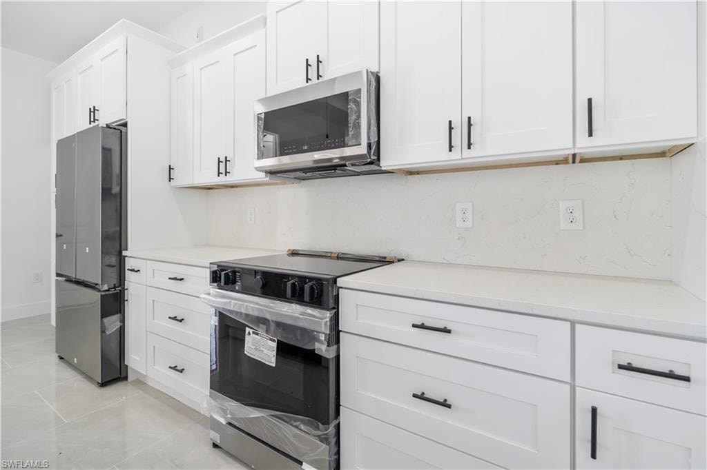 Modern kitchen featuring white shaker cabinetry with matte black hardware