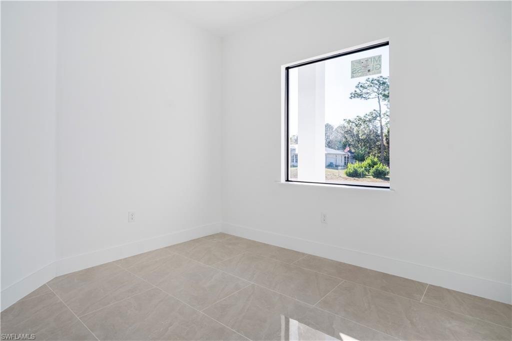 Room featuring a large picture window, light-toned tile flooring, white walls, and white baseboards
