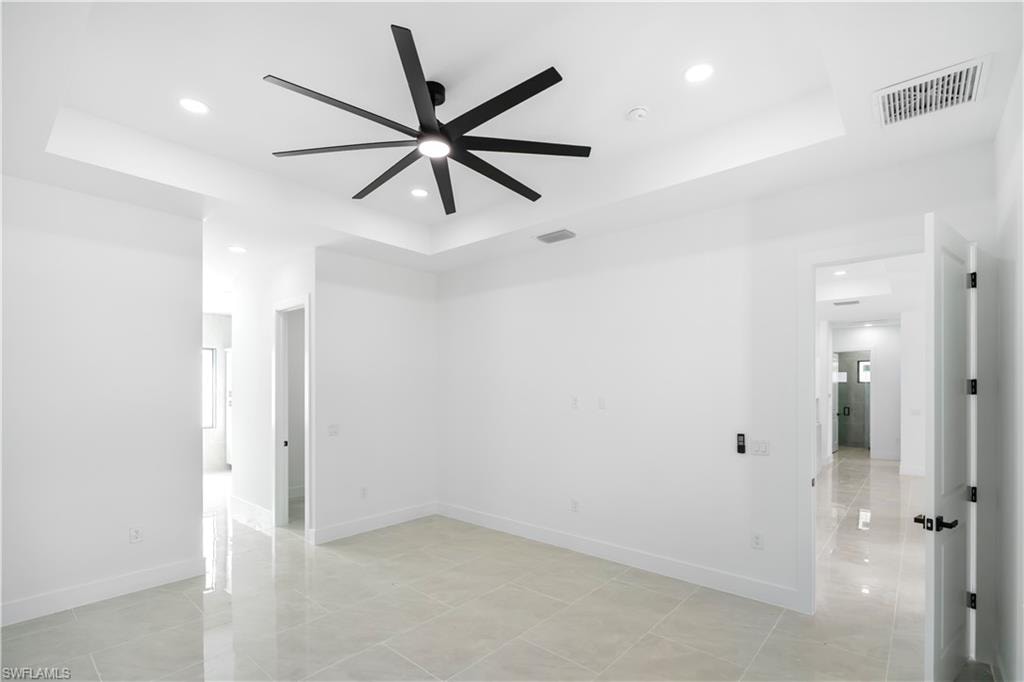 Spacious room with a tray ceiling, recessed lighting, and a modern black ceiling fan