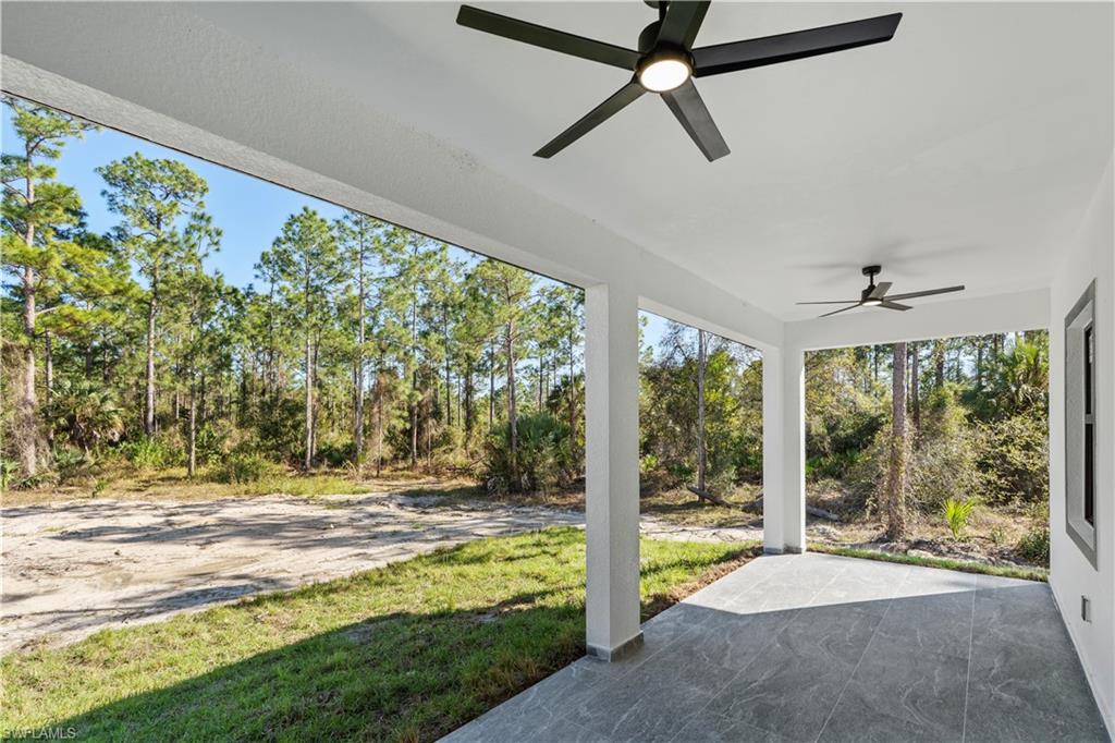 Covered patio featuring gray large-format tile flooring, white structural columns, and two black ceiling fans with integrated lighting