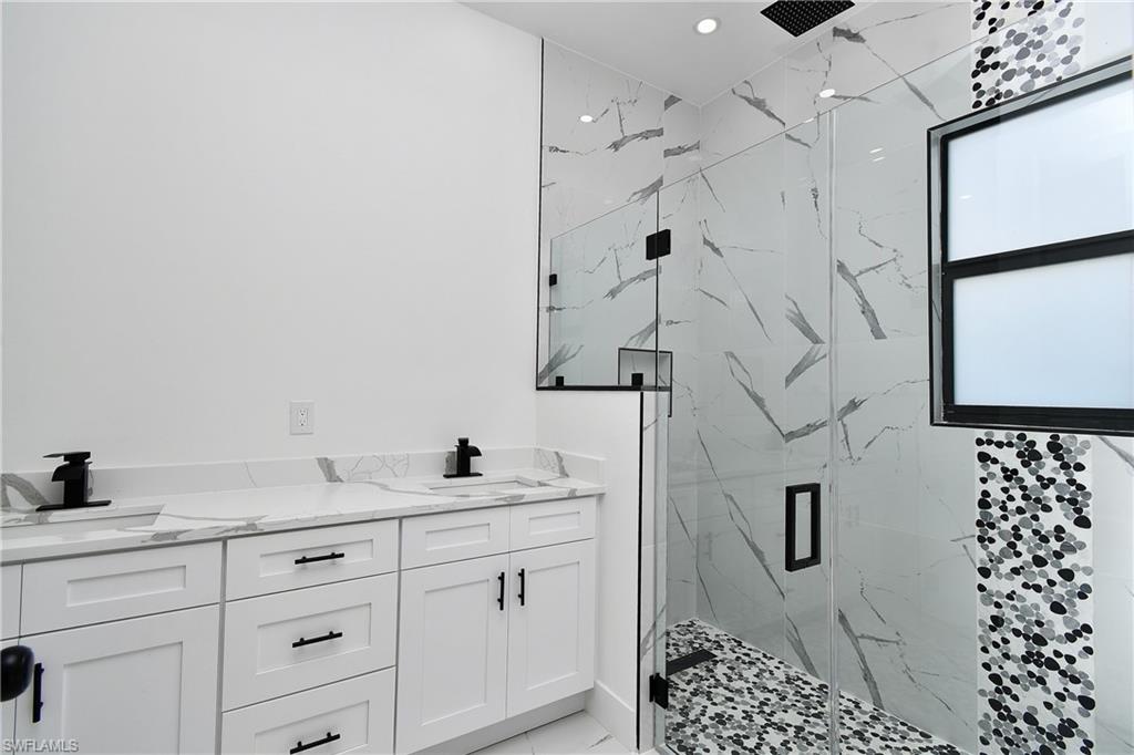 Bathroom featuring a double vanity with white cabinetry and stone countertops