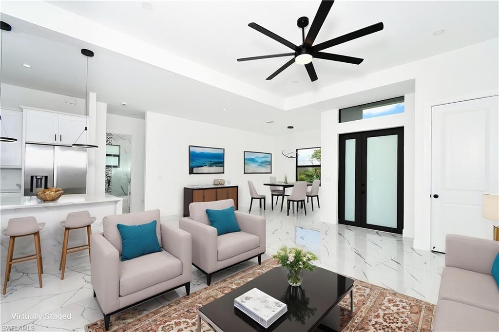 Open-concept living space featuring high ceilings with a modern ceiling fan, large format tile flooring, and contemporary lighting fixtures