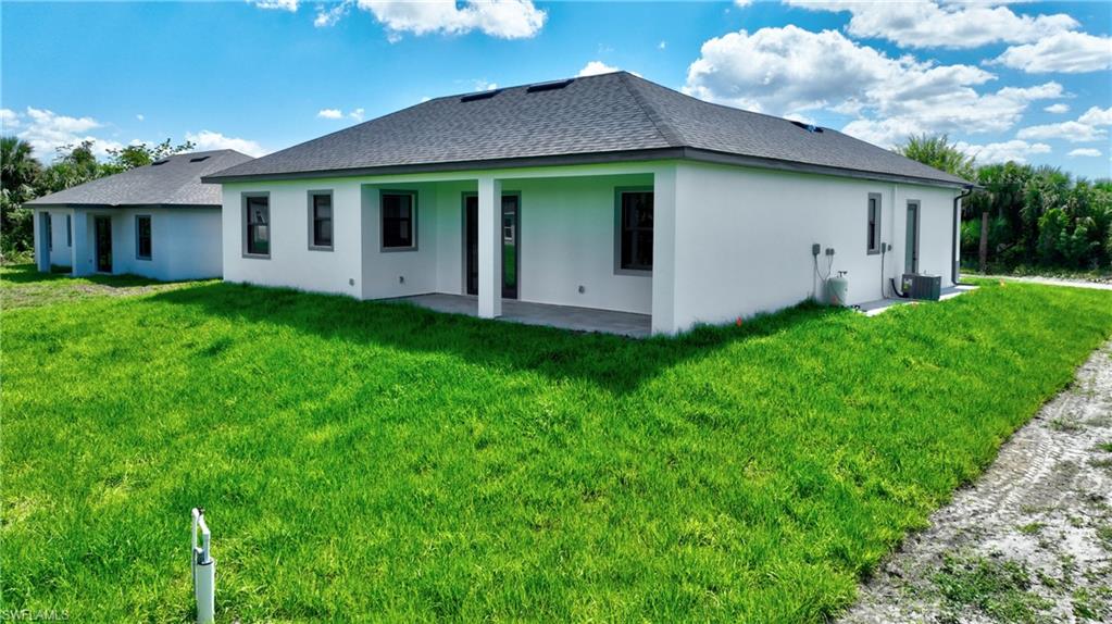 Contemporary exterior featuring a covered patio, dark shingle roof, and white stucco finish