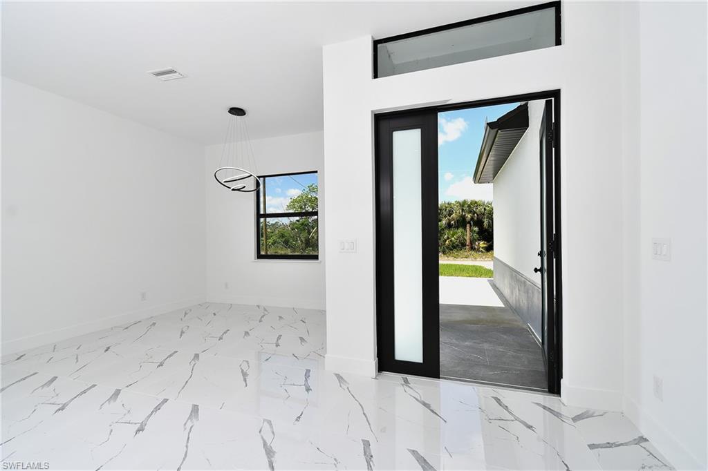 Modern entry area featuring a wide front door with frosted glass panel and transom window