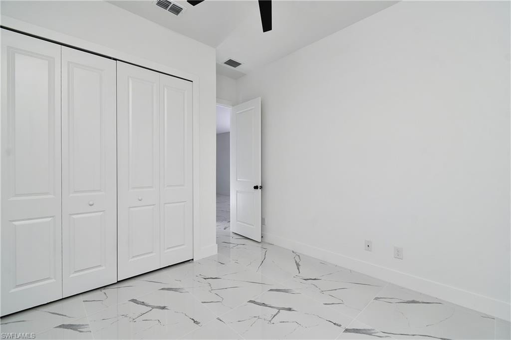 White panel bi-fold closet doors complement the light-toned walls and large format tile flooring