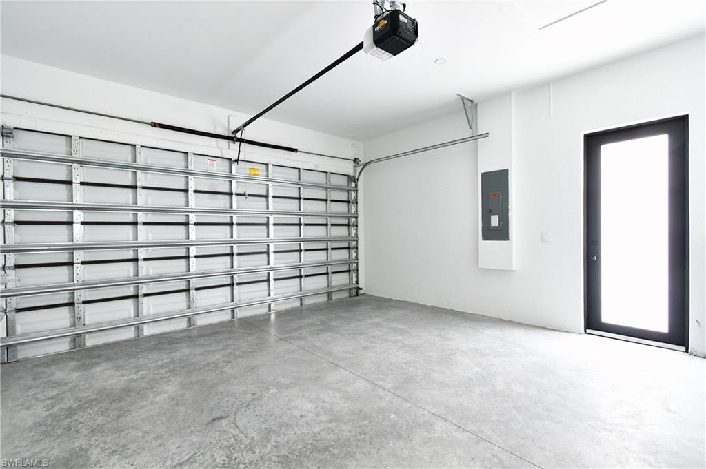 Spacious garage featuring a concrete floor, white walls, and an automatic garage door opener