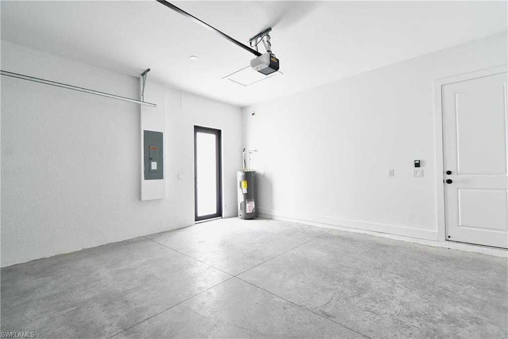 Spacious garage featuring a concrete floor, bright white walls, a side-entry door with a dark frame, and a white panel door