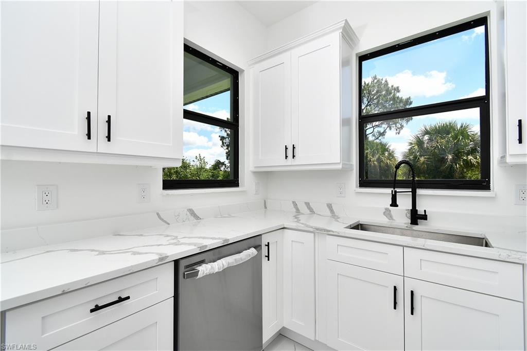 Modern kitchen featuring white shaker cabinetry with matte black hardware, white countertops with grey veining, a stainless steel undermount sink, and a black gooseneck faucet
