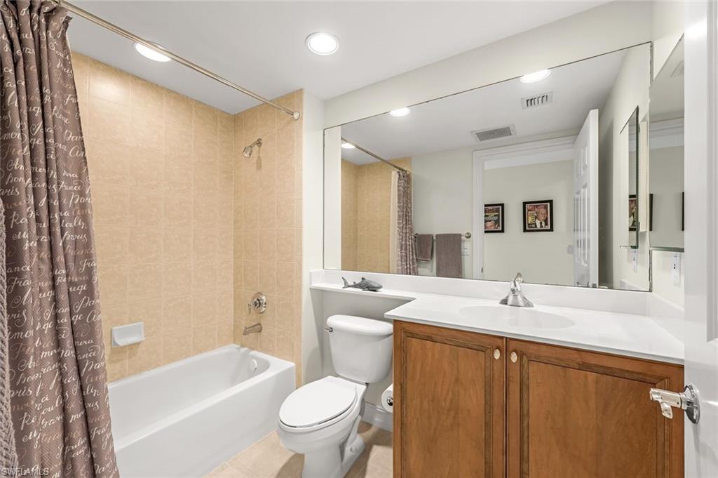 Full bathroom with tile patterned floors, toilet, shower / bath combination with curtain, and vanity