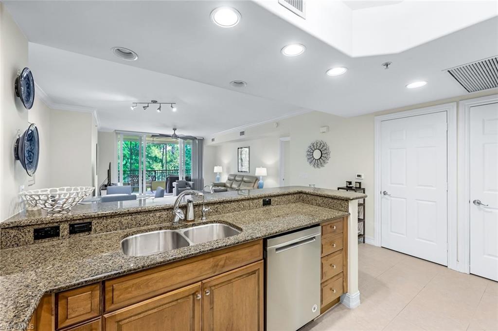 Kitchen with sink, light tile patterned floors, dishwasher, and light stone countertops