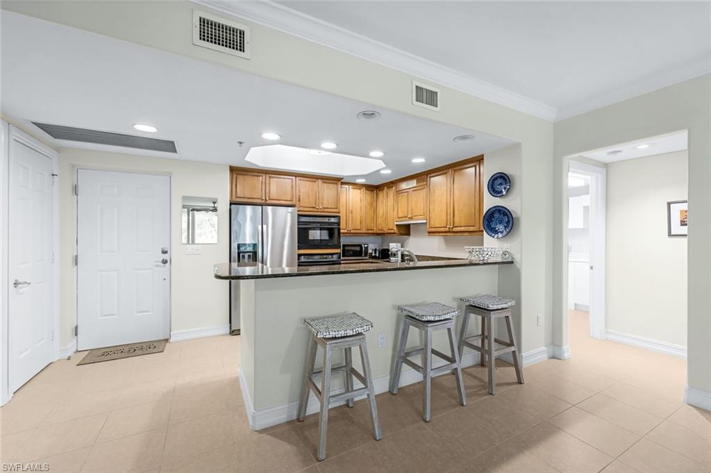Kitchen featuring light tile patterned floors, a kitchen bar, kitchen peninsula, and stainless steel appliances