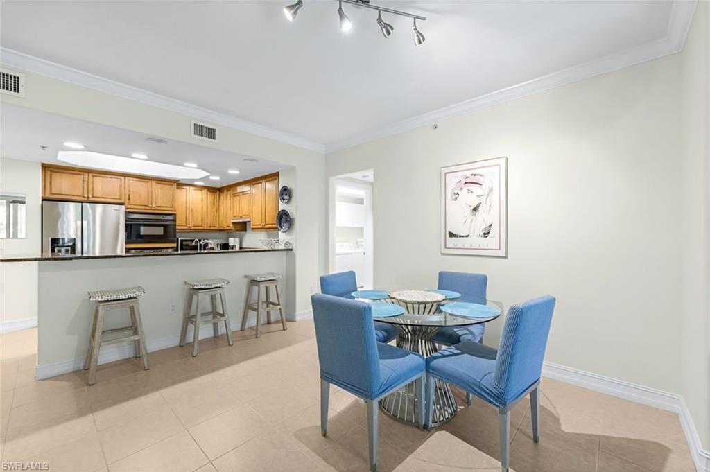 Dining space featuring rail lighting, crown molding, and light tile patterned floors