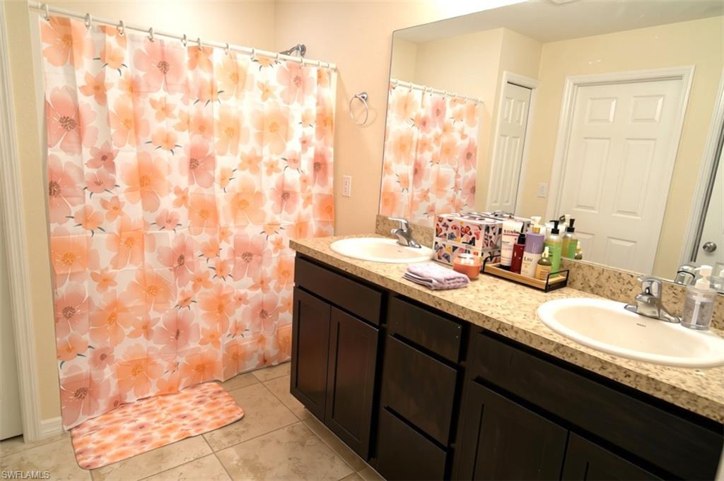 Dual vanity featuring integrated sinks, speckled countertops, and dark wood-finish cabinetry