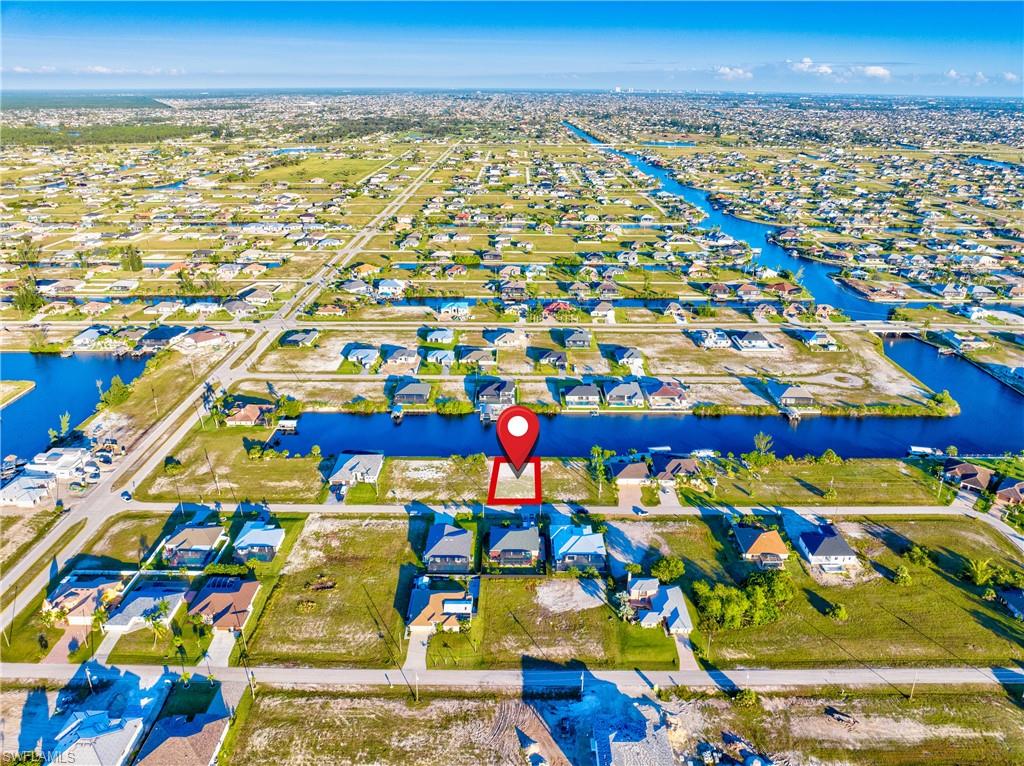 Aerial perspective showcasing a residential lot marked by a red pin, surrounded by similar properties