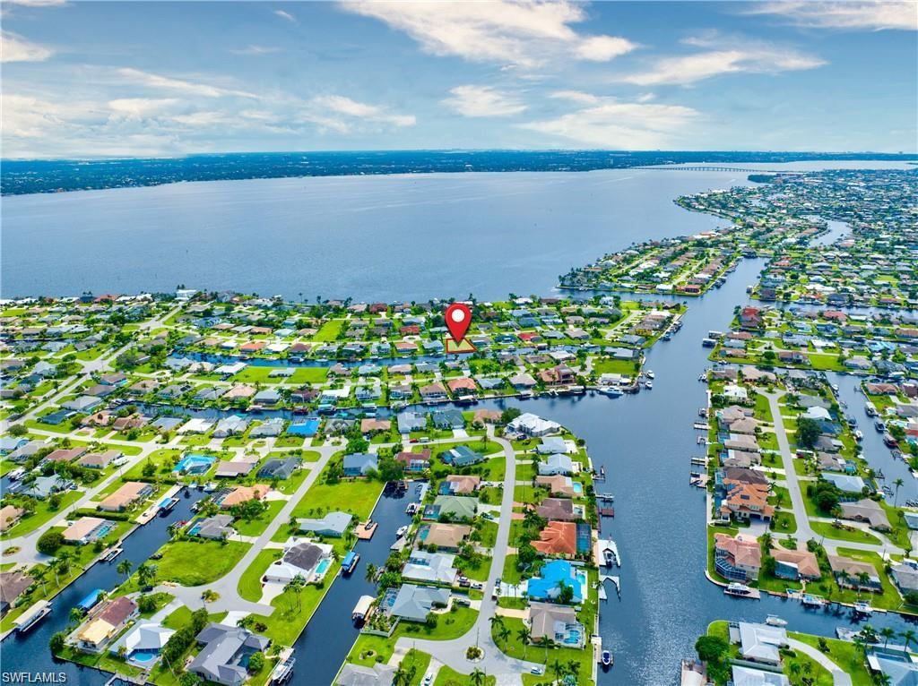 Aerial perspective showcasing a residential area featuring numerous properties, extensive canal systems, a large body of water, and a distant bridge