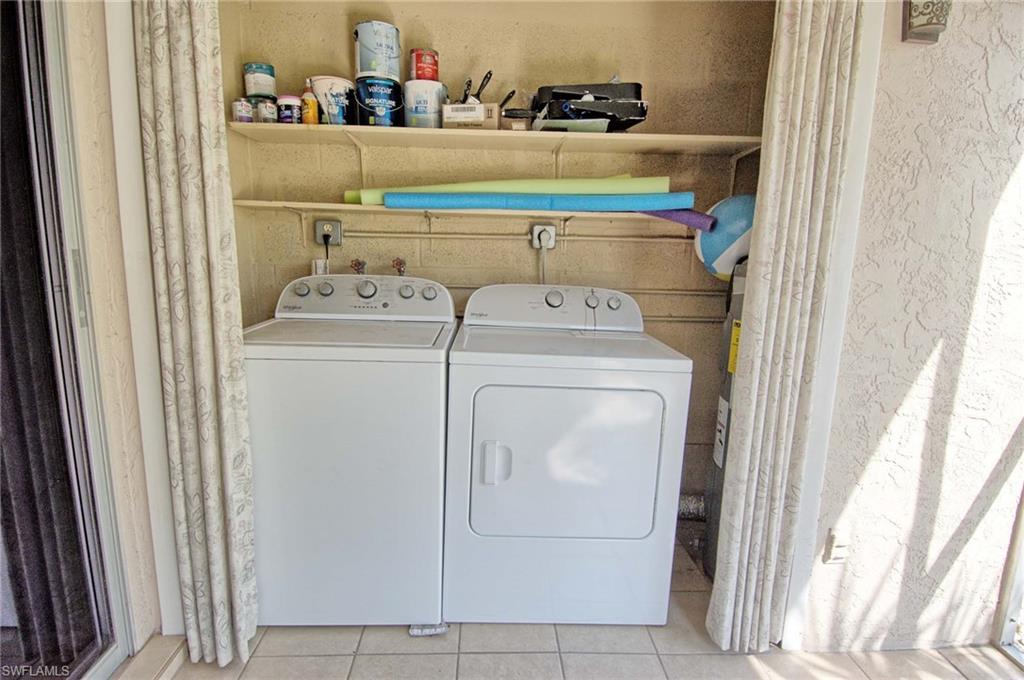 Dedicated laundry area featuring a white washing machine and dryer, tile flooring, and integrated shelving