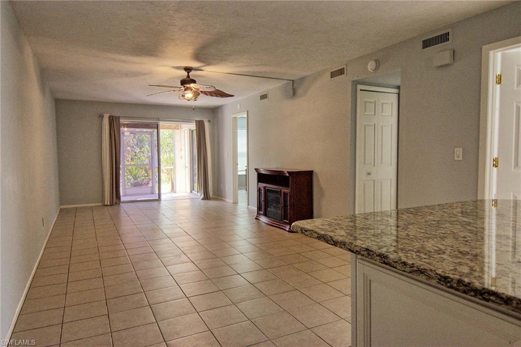 Spacious open-concept room featuring tile flooring, a ceiling fan with integrated lighting, sliding glass doors to the exterior, and a built-in media console with an electric fireplace