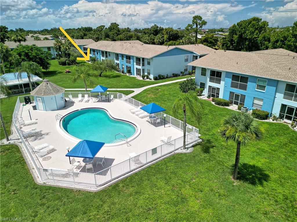 Heart-shaped swimming pool with a surrounding paved deck, white perimeter fencing, and two blue shade canopies