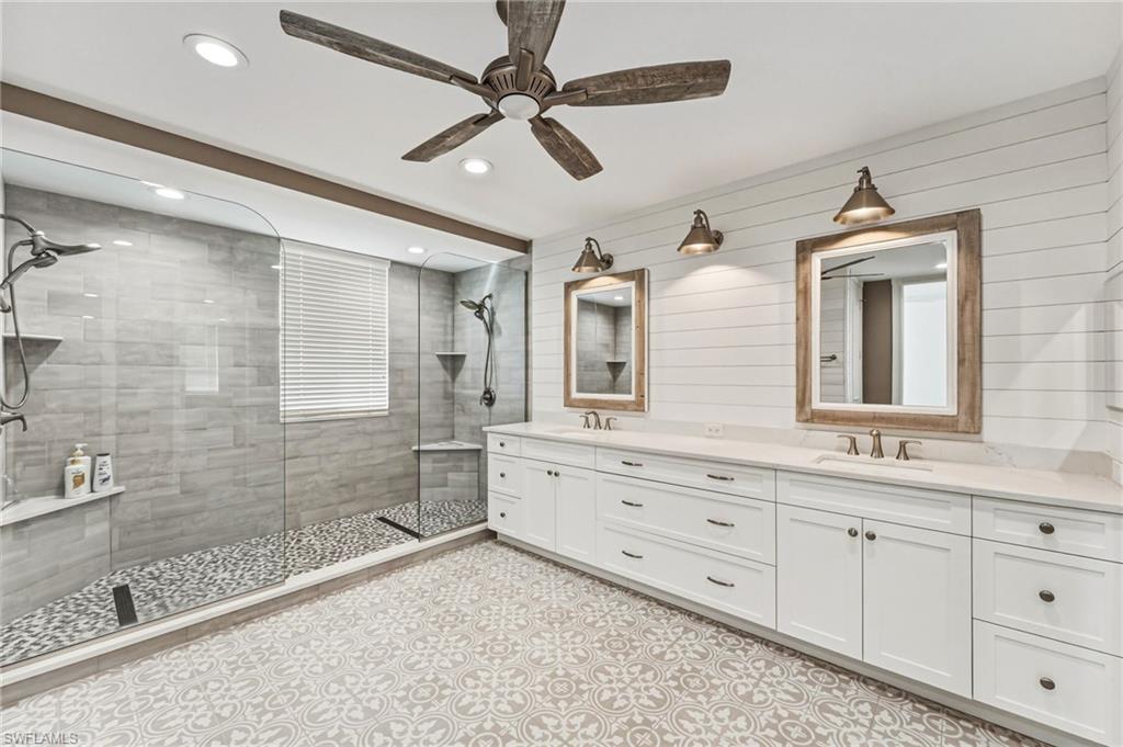 The oversized, reimagined shower evokes a true spa experience, complete with a seamless glass enclosure, floor-to-ceiling subway tile, dual shower heads, shiplap walls and beautifully appointed tile flooring underfoot—offering a daily sense of indulgent, resort-inspired relaxation.