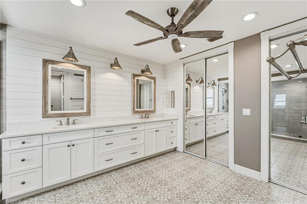 The primary bathroom evokes a true spa-like retreat, featuring dual vanities adorned with quartz countertops, a generous walk-in closet, and custom mirrors paired with designer lighting. Abundant drawers and thoughtfully designed storage complete the space with both elegance and functionality.