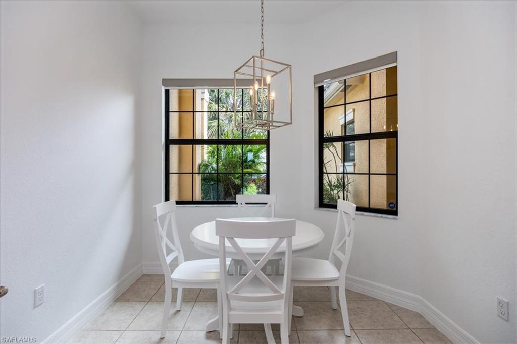 Dining space with light tile patterned flooring, a healthy amount of sunlight, and a notable chandelier