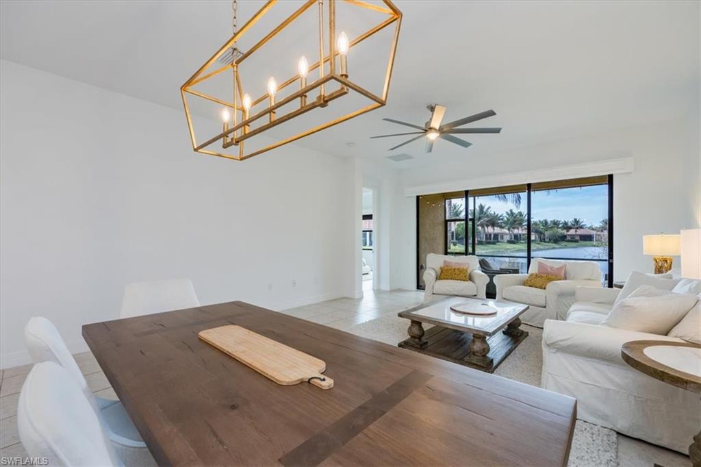 Tiled living room with ceiling fan with notable chandelier