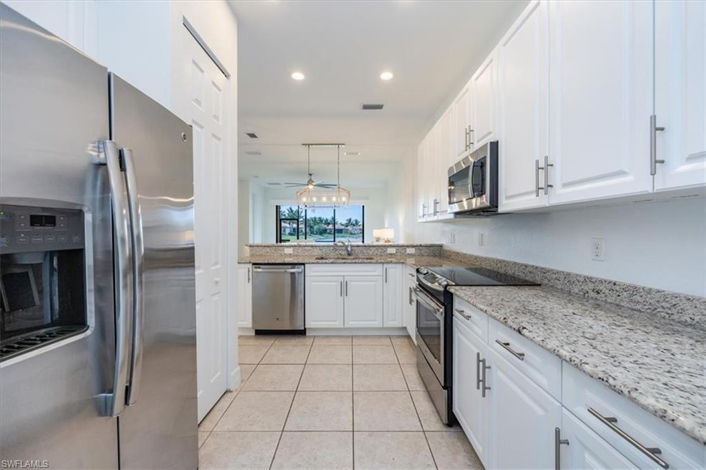 Kitchen featuring appliances with stainless steel finishes, hanging light fixtures, ceiling fan, sink, and white cabinetry