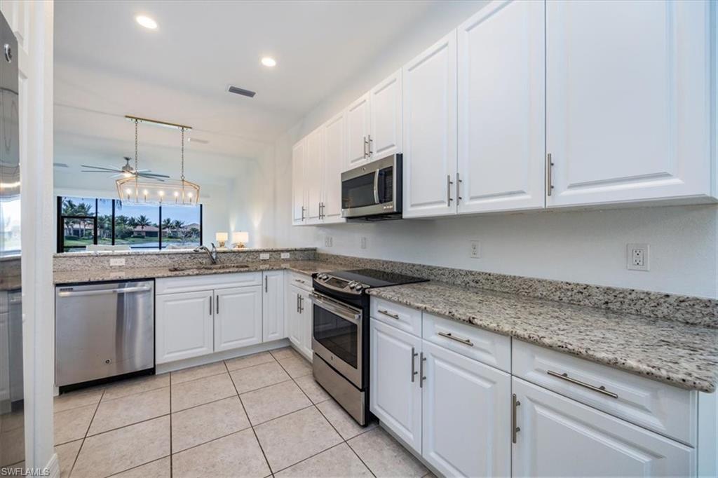 Kitchen featuring stainless steel appliances, white cabinets, ceiling fan, and pendant lighting