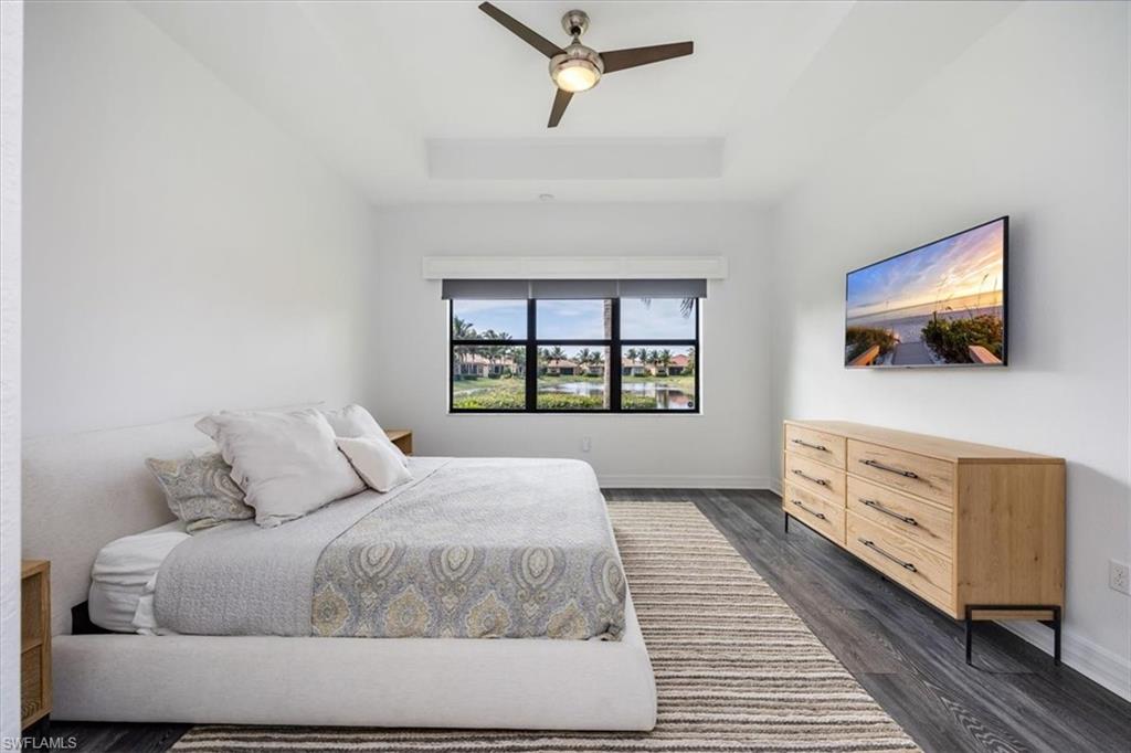 Bedroom with ceiling fan, dark wood-type flooring, and a raised ceiling
