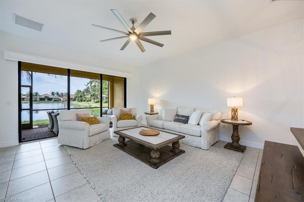 Tiled living room with ceiling fan and a water view