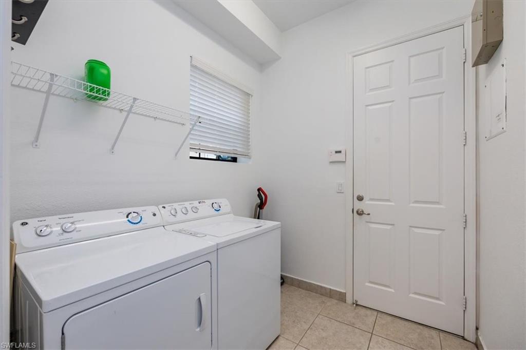 Clothes washing area with light tile patterned floors and separate washer and dryer