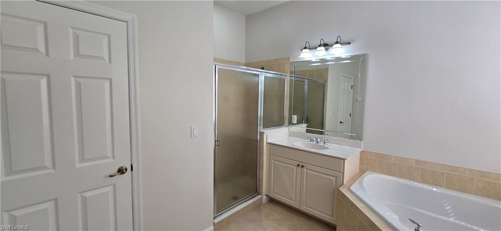 Full bathroom featuring vanity, a garden tub, a shower stall, and light tile patterned flooring