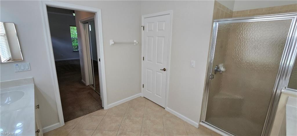Full bathroom with 2 vanities, a shower stall, light tile patterned floors.