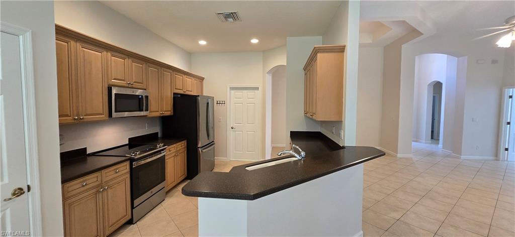 Kitchen with stainless steel appliances, a breakfast bar, dark countertops, and recessed lighting