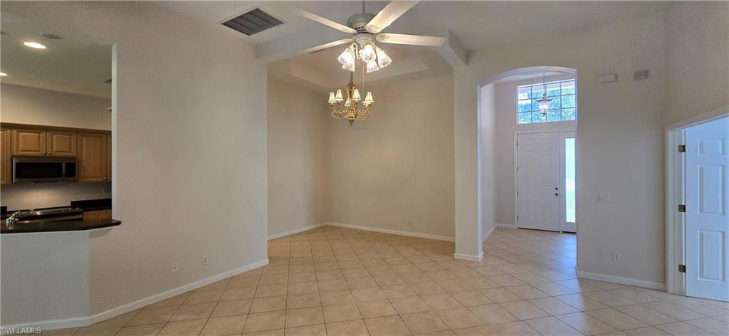 Features a chandelier, light tile floors, and a towering ceiling