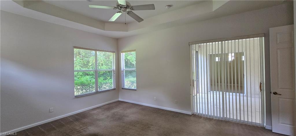 Spacious primary bedroom with a tray ceiling, ceiling fan and sliding doors to lanai.