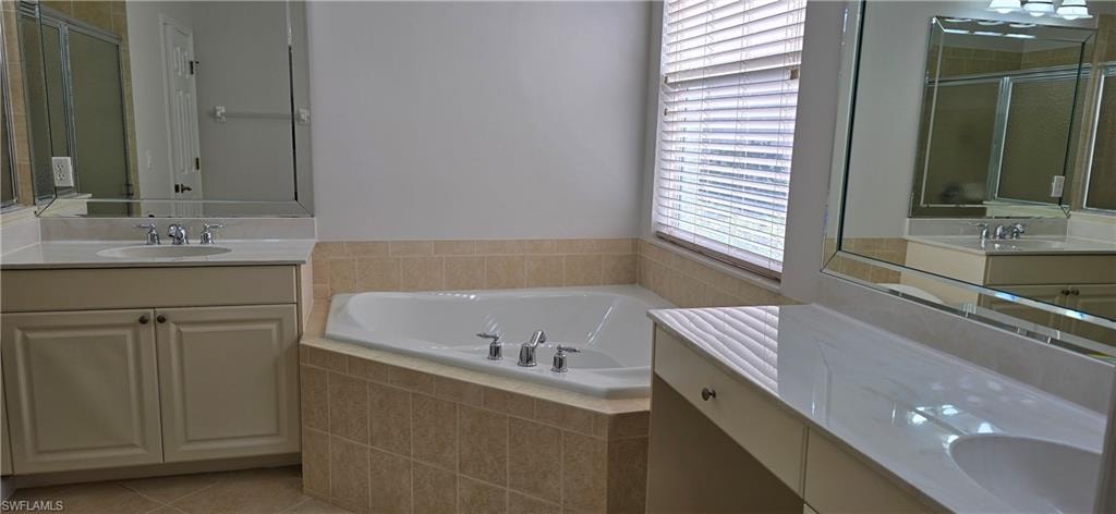 Full bath with two vanities, a garden tub, a shower stall, and light tile patterned flooring