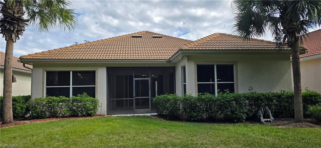 Rear view of property with screened lanai, and tile roof.