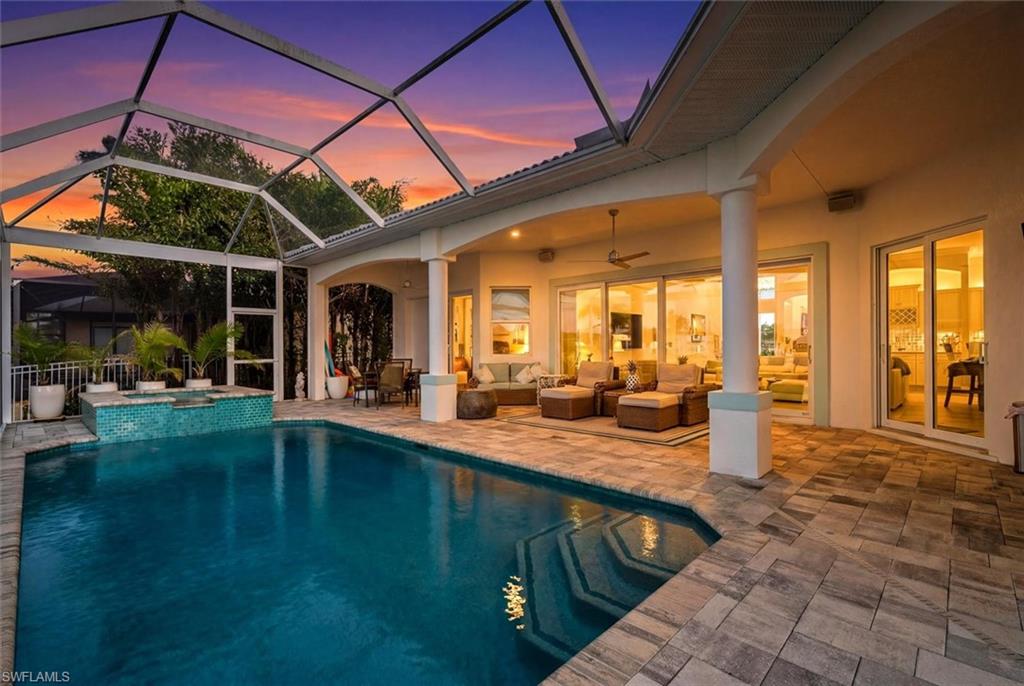 Screened outdoor living area featuring a rectangular pool and integrated spa with blue tile accents