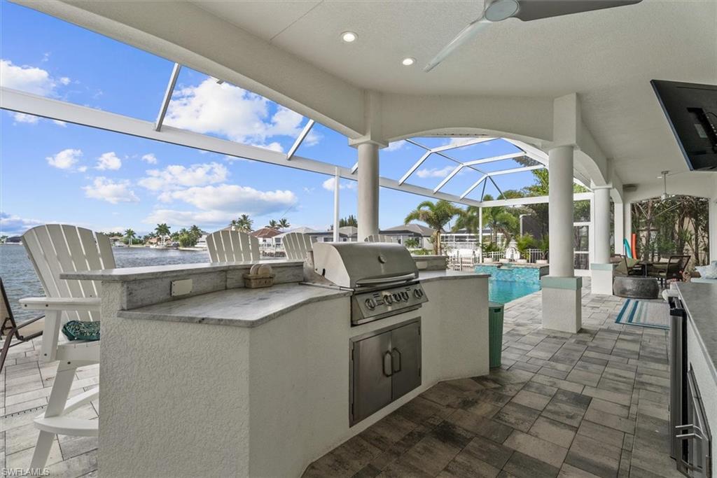 Covered patio featuring an outdoor kitchen with built-in grill, stone countertops, and integrated cabinetry