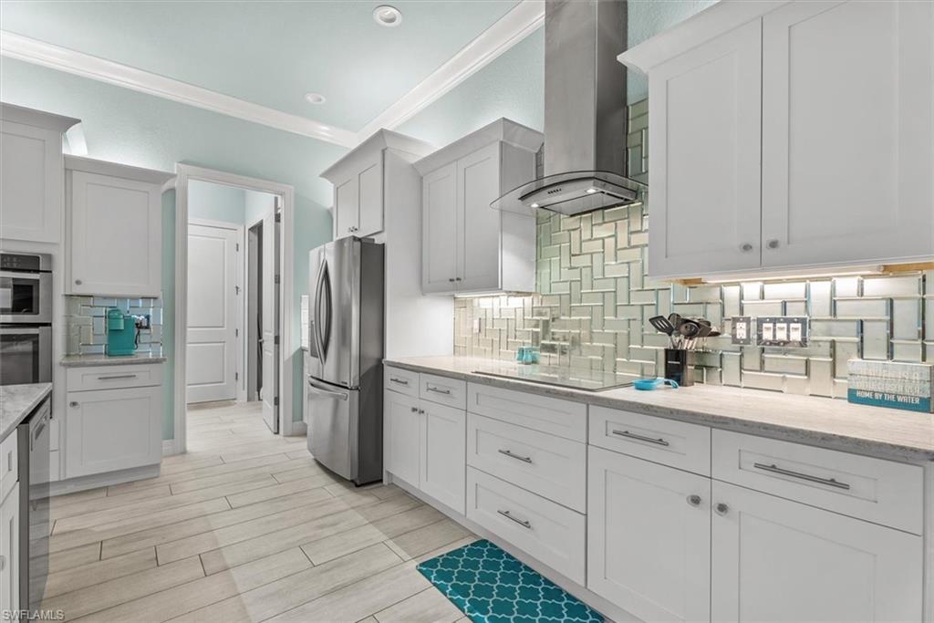 Kitchen featuring white shaker-style cabinetry, stainless steel appliances, a light-toned countertop, a herringbone-patterned glass tile backsplash, and recessed lighting