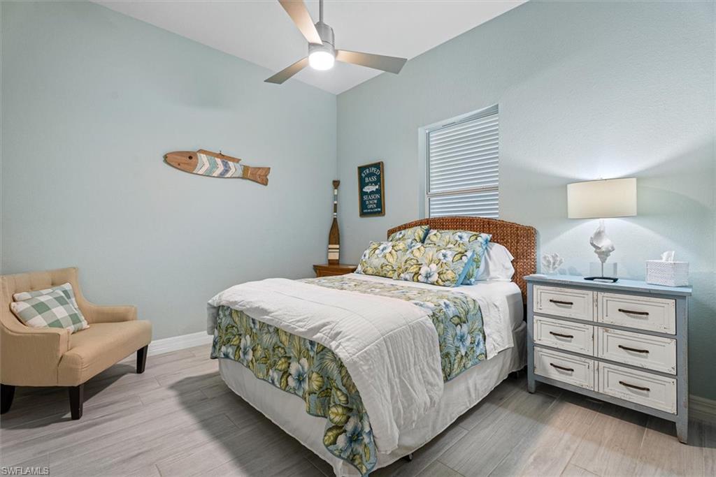 Vaulted ceilings featuring a ceiling fan with integrated lighting, a window with horizontal blinds, and wood-finish flooring