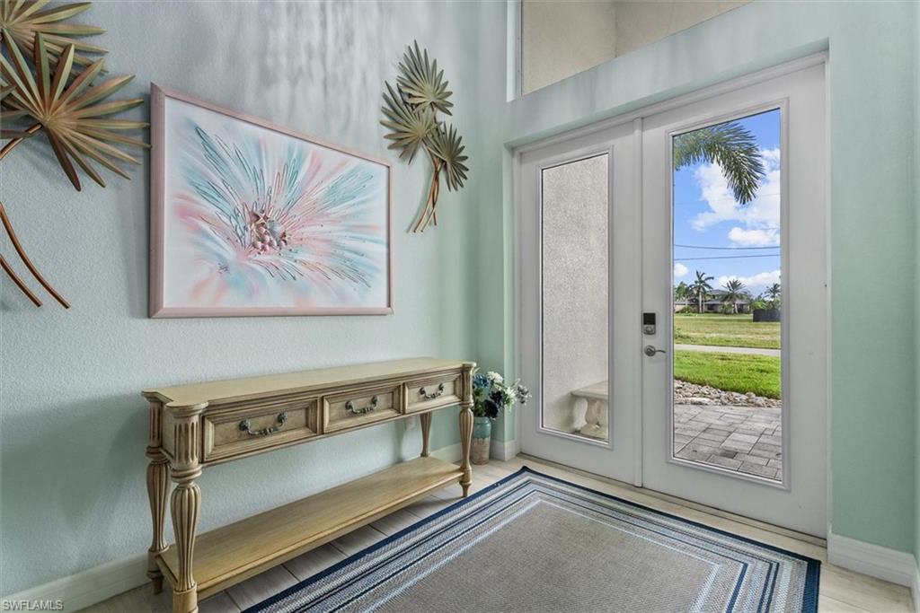 Entryway featuring double glass-panel doors with transom window above, light-toned wall finish, and a decorative console table with carved details