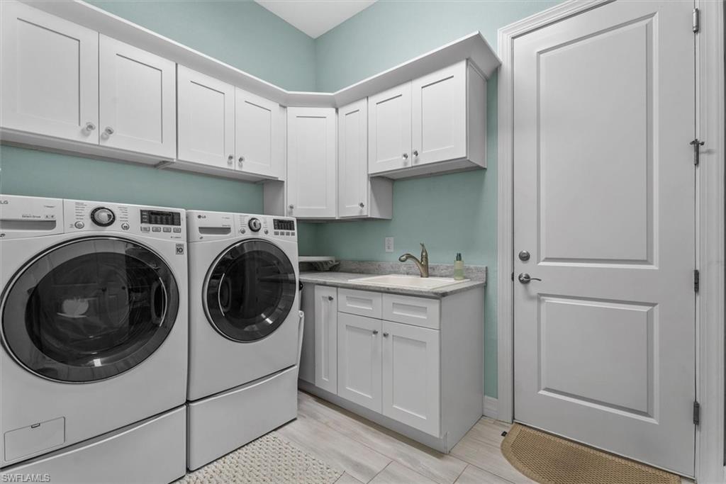 Dedicated utility room featuring abundant white shaker-style cabinetry, a built-in sink with a gooseneck faucet, light-toned countertops, and wood-finish flooring